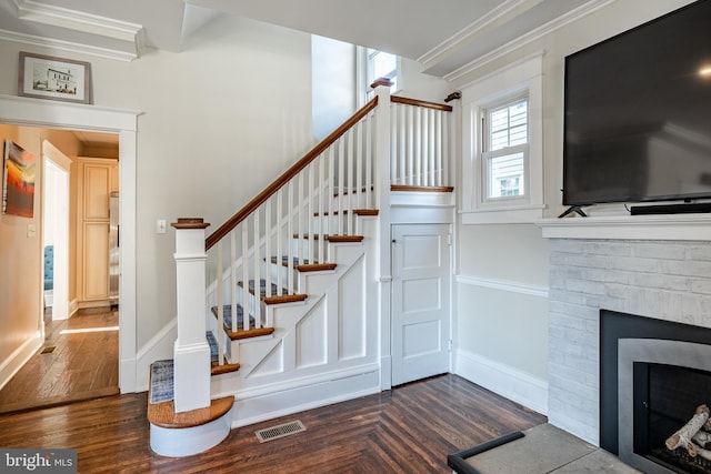 staircase with a fireplace, hardwood / wood-style floors, and ornamental molding