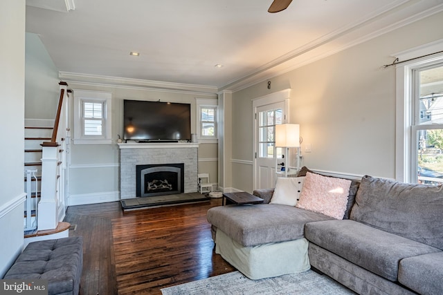 living room with ceiling fan, wood-type flooring, crown molding, and a brick fireplace