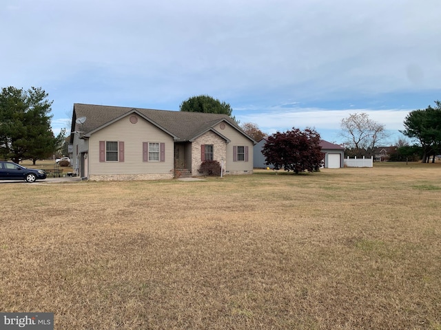 single story home featuring a garage, an outdoor structure, and a front lawn