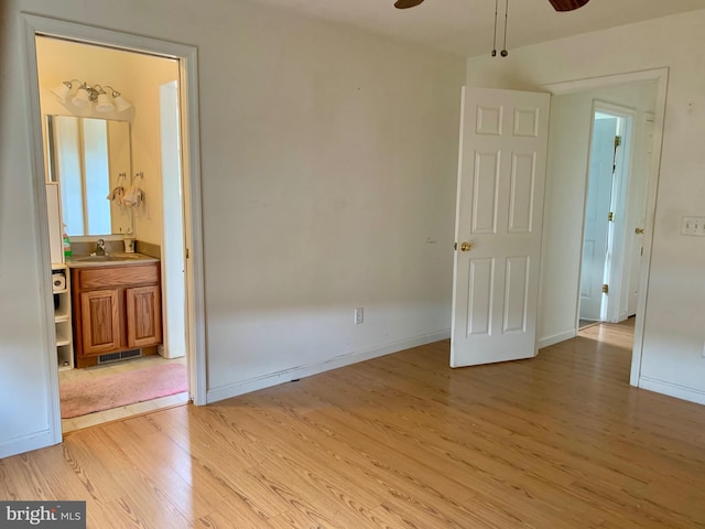 empty room with light hardwood / wood-style floors, ceiling fan, and sink