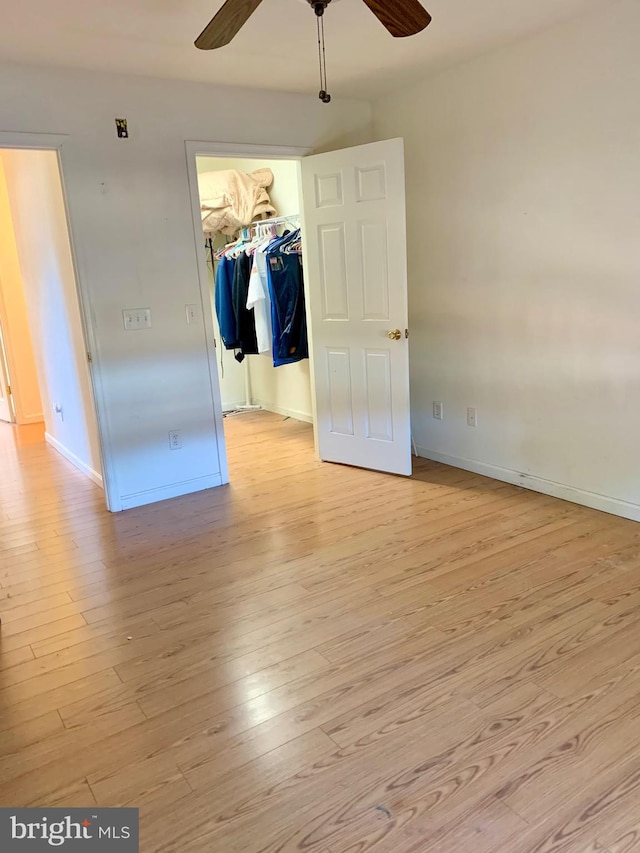 unfurnished bedroom with ceiling fan, light hardwood / wood-style floors, a walk in closet, and a closet