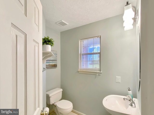 bathroom with sink, a textured ceiling, and toilet