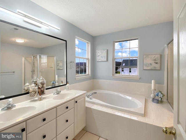 bathroom with tile patterned flooring, vanity, shower with separate bathtub, and a textured ceiling