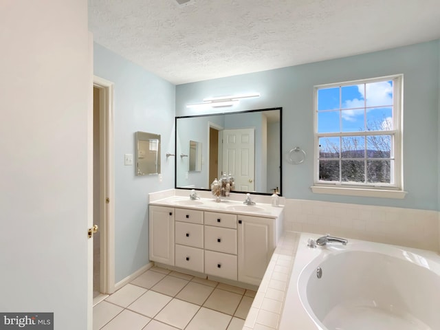 bathroom with vanity, a tub to relax in, tile patterned floors, and a textured ceiling