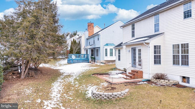 rear view of property with a wooden deck and a lawn