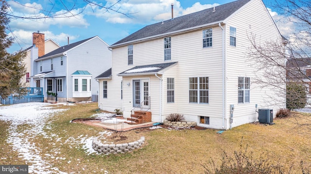 snow covered rear of property with a yard and cooling unit