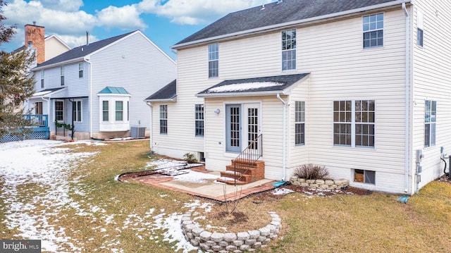 snow covered rear of property with a lawn and central air condition unit