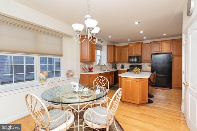 kitchen with a center island, sink, hanging light fixtures, light hardwood / wood-style floors, and black appliances