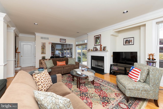 living room featuring light wood-type flooring, crown molding, and a healthy amount of sunlight