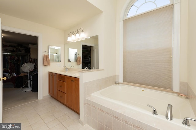 bathroom featuring tile patterned flooring, a relaxing tiled tub, and vanity