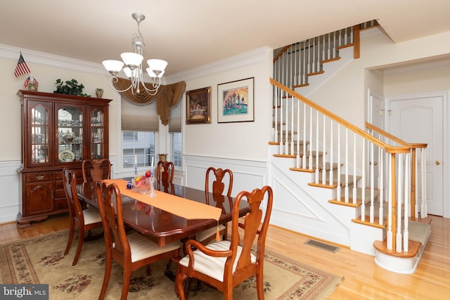 dining area featuring hardwood / wood-style flooring, an inviting chandelier, and crown molding