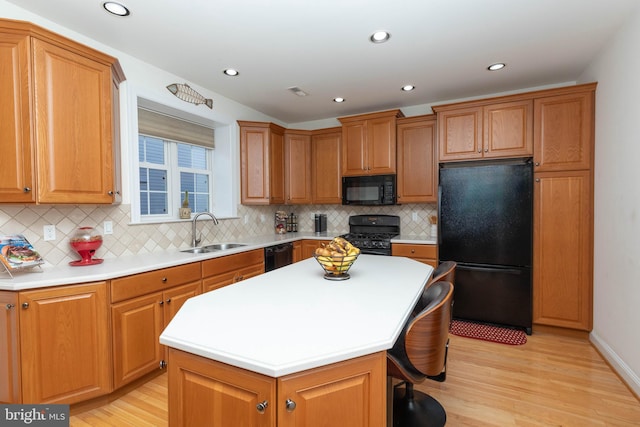 kitchen with black appliances, sink, a kitchen island, tasteful backsplash, and light hardwood / wood-style floors