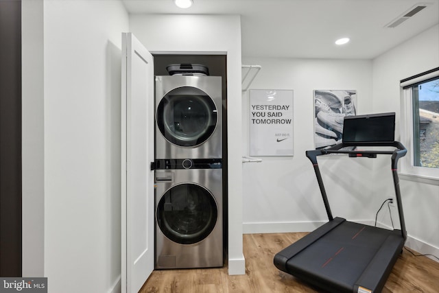 laundry room featuring hardwood / wood-style floors and stacked washer / drying machine