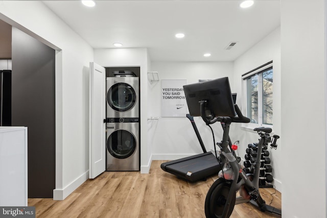 workout room with stacked washer / drying machine and light hardwood / wood-style flooring