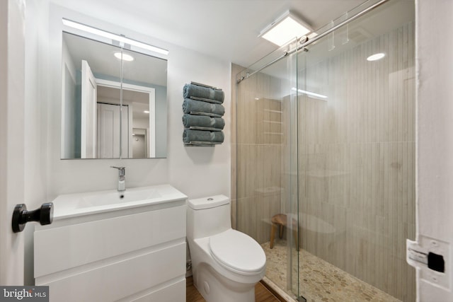 bathroom featuring a shower with shower door, toilet, and vanity