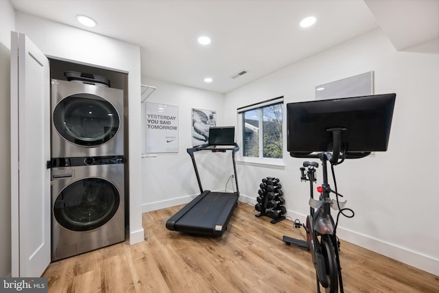 workout area featuring stacked washer and dryer and hardwood / wood-style flooring