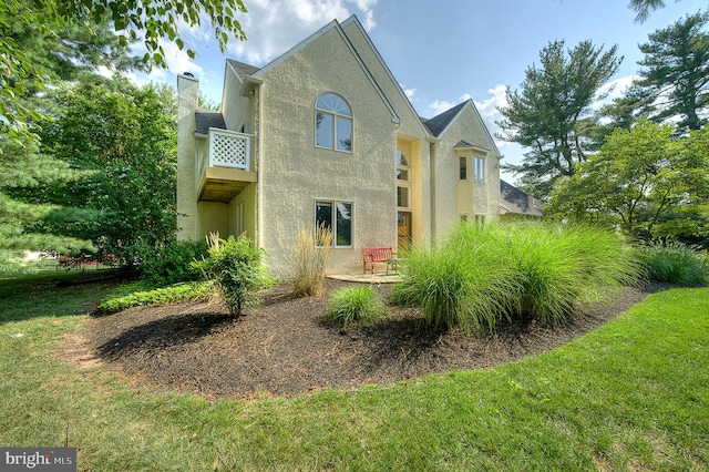 view of front of property featuring a balcony and a front yard