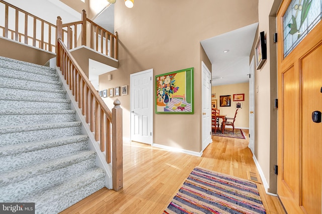 foyer entrance with wood-type flooring and a towering ceiling