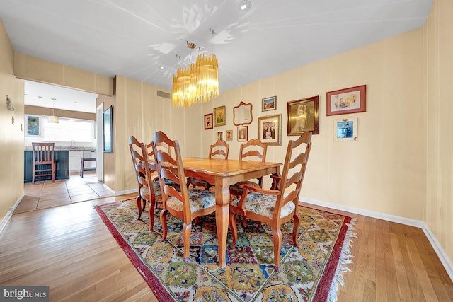 dining space with a chandelier and light hardwood / wood-style floors