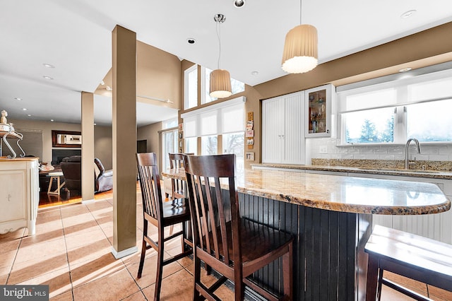 kitchen with white cabinets, a kitchen breakfast bar, light stone counters, and plenty of natural light