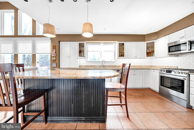 kitchen with stainless steel appliances, plenty of natural light, hanging light fixtures, and a breakfast bar area