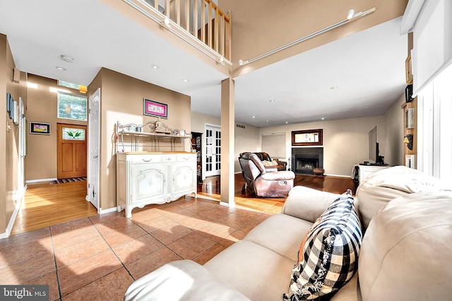 living room featuring a fireplace, light hardwood / wood-style flooring, and a high ceiling