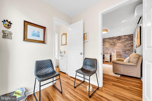 living area featuring a wall mounted AC, light hardwood / wood-style floors, and brick wall