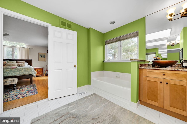 bathroom featuring tile patterned floors, vanity, a tub, and a chandelier