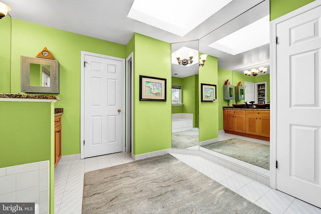 bathroom with tile patterned flooring, vanity, a bath, and a notable chandelier