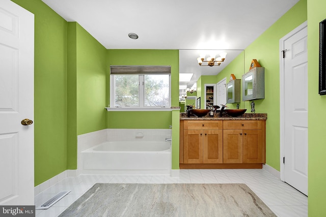 bathroom with tile patterned flooring, vanity, a tub to relax in, and a notable chandelier