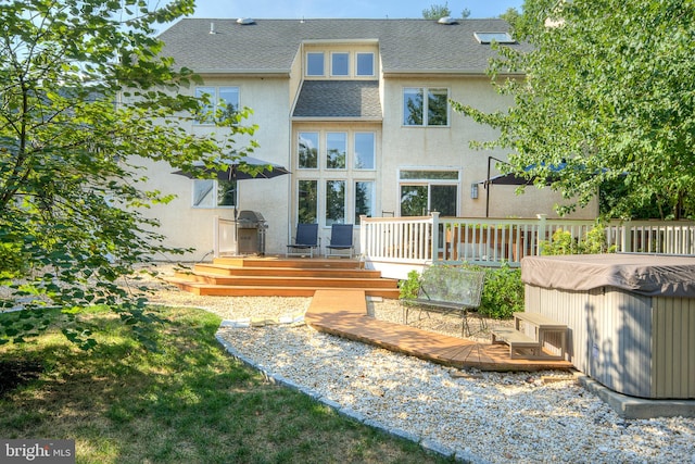 rear view of property with a deck and a hot tub