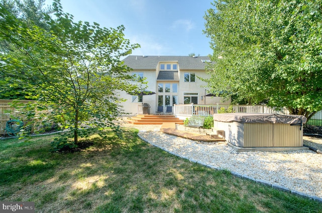 back of house featuring a lawn, a deck, and a hot tub