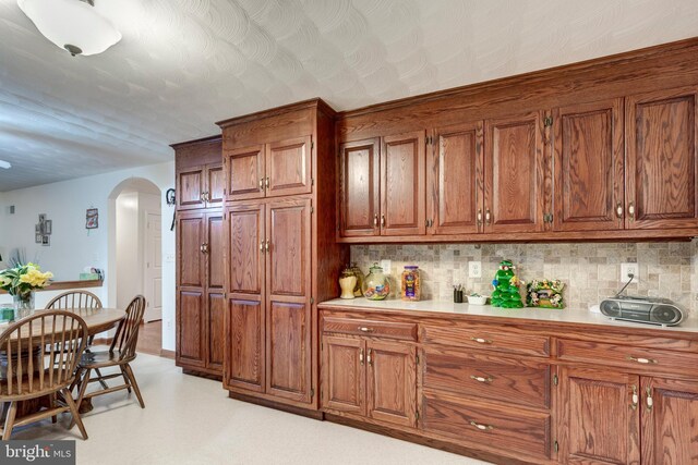 310 Updyke Rd, Littlestown, PA 17340 - kitchen with arched walkways, brown cabinetry, backsplash, and light countertops