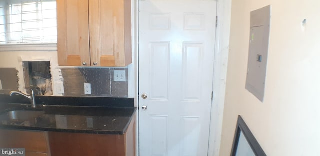 kitchen featuring backsplash, electric panel, and sink