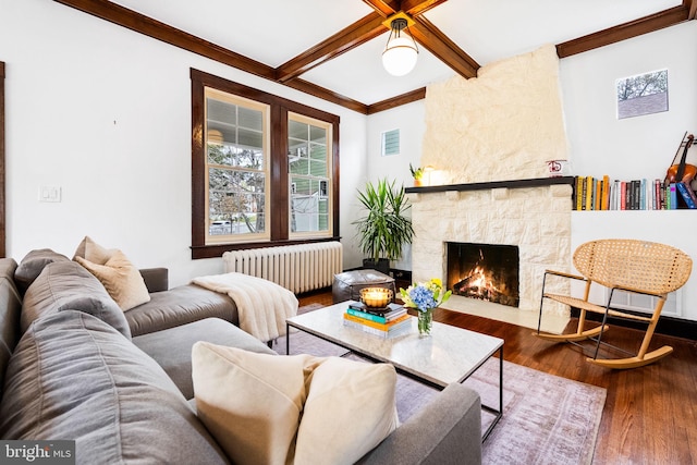 living room with radiator, crown molding, a fireplace, beamed ceiling, and wood-type flooring