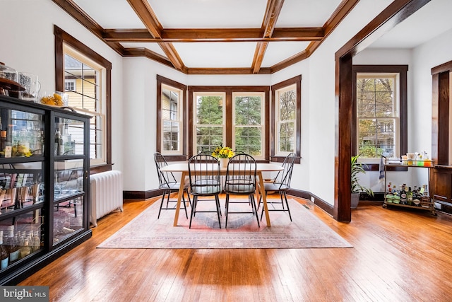 dining area featuring beam ceiling, wood-type flooring, radiator heating unit, and coffered ceiling