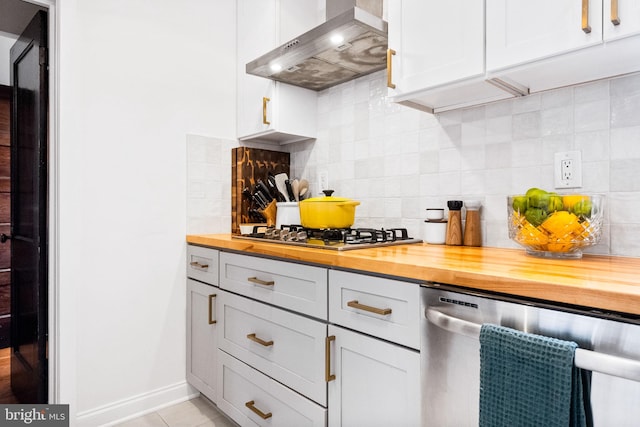 kitchen featuring backsplash, wood counters, wall chimney range hood, and appliances with stainless steel finishes