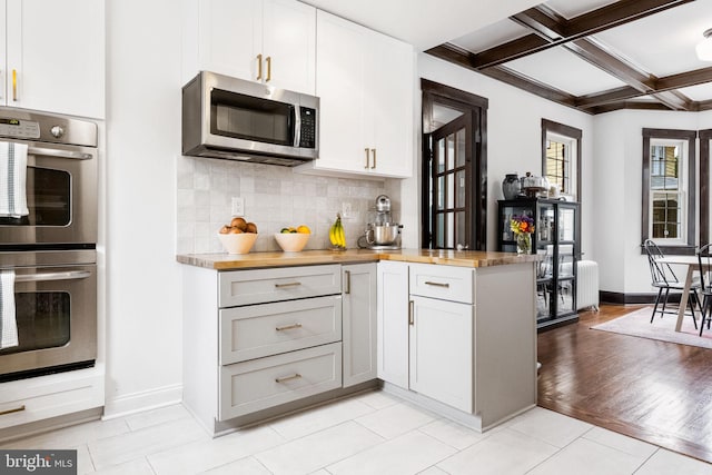 kitchen featuring stainless steel appliances, coffered ceiling, wooden counters, light hardwood / wood-style floors, and white cabinets