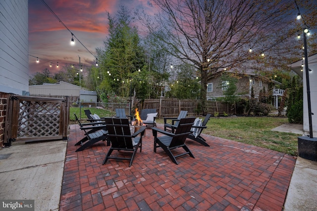 patio terrace at dusk with an outdoor fire pit and a lawn