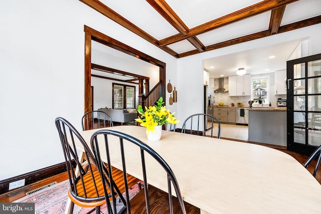 dining space with beamed ceiling and light hardwood / wood-style floors