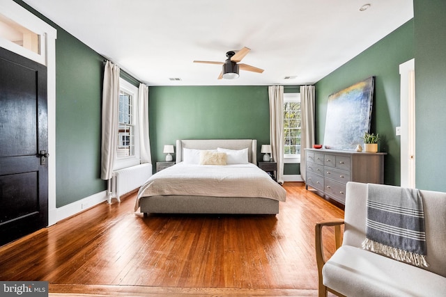 bedroom with light hardwood / wood-style flooring, radiator, and ceiling fan