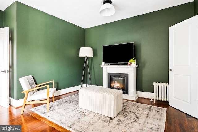 living area with dark hardwood / wood-style flooring and radiator