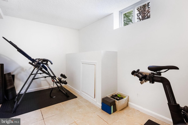 exercise room with light tile patterned flooring and a textured ceiling