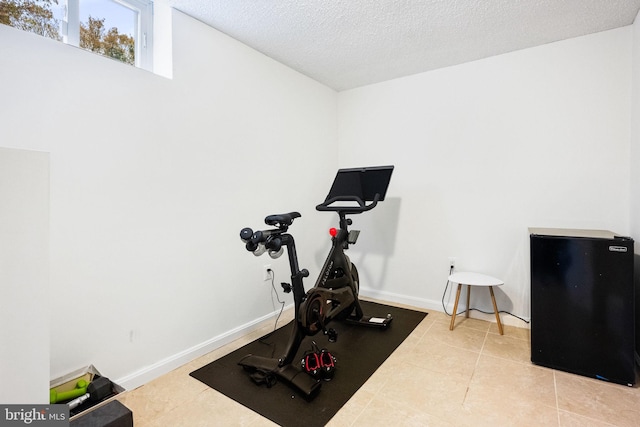 workout area featuring light tile patterned flooring and a textured ceiling