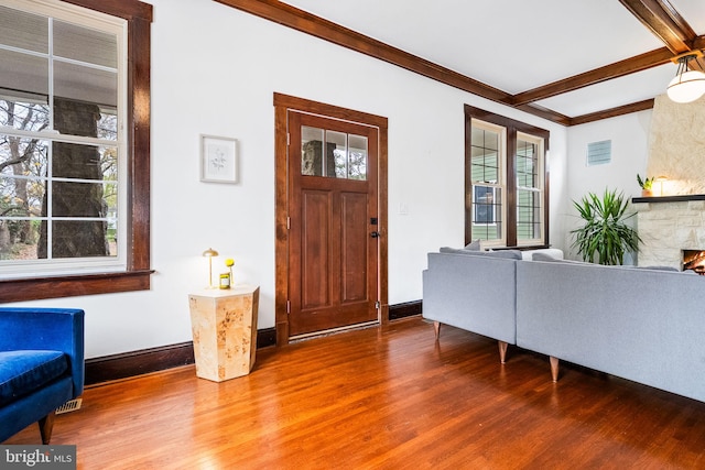 entryway with a fireplace, hardwood / wood-style floors, crown molding, and beam ceiling