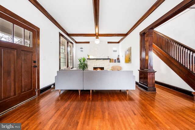 unfurnished living room featuring beamed ceiling, a large fireplace, hardwood / wood-style flooring, and crown molding