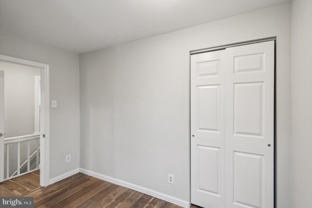 unfurnished bedroom with dark hardwood / wood-style floors and a closet