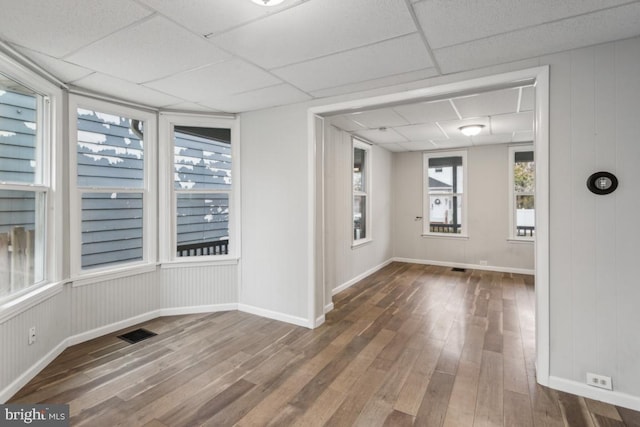 spare room with a paneled ceiling and dark hardwood / wood-style floors