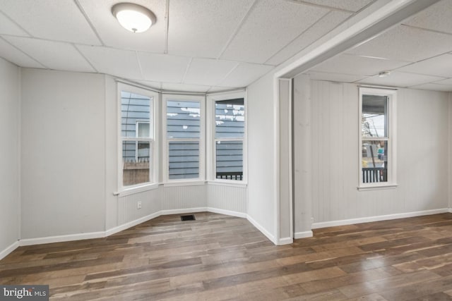 empty room with dark hardwood / wood-style flooring and a paneled ceiling