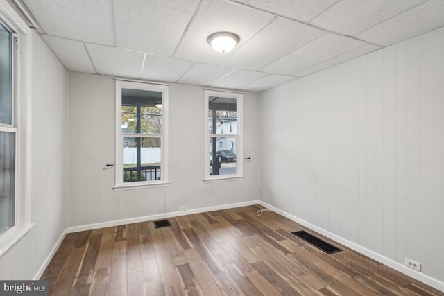 unfurnished room with hardwood / wood-style floors and a drop ceiling